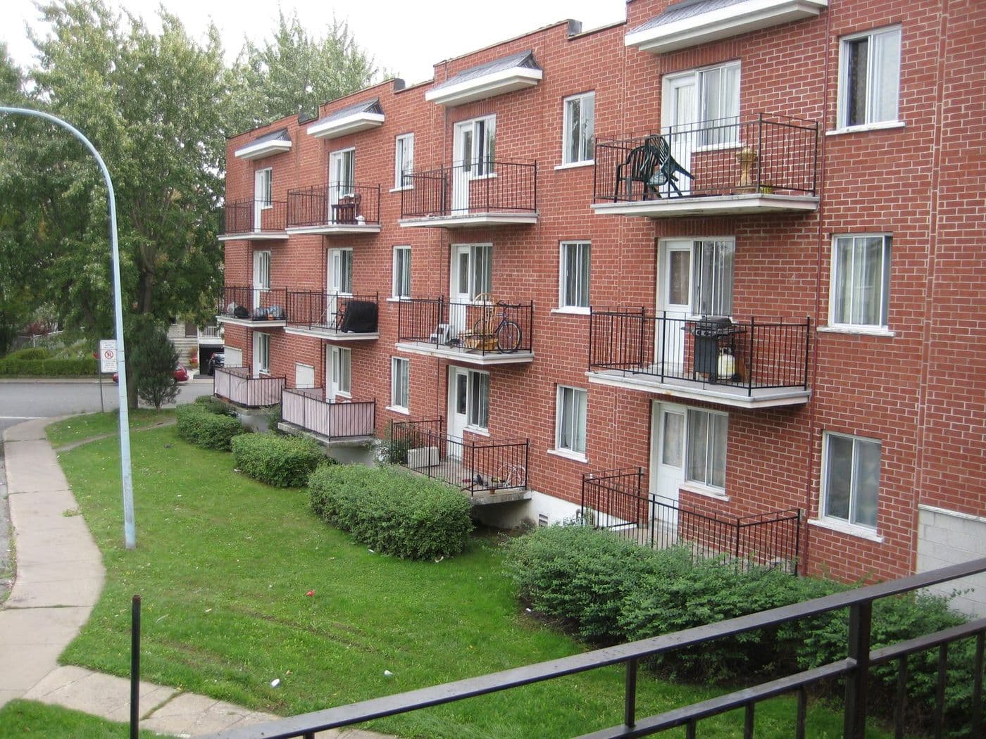 Side view of a PGK apartment building and grounds on a quiet, tree-lined Montréal street
