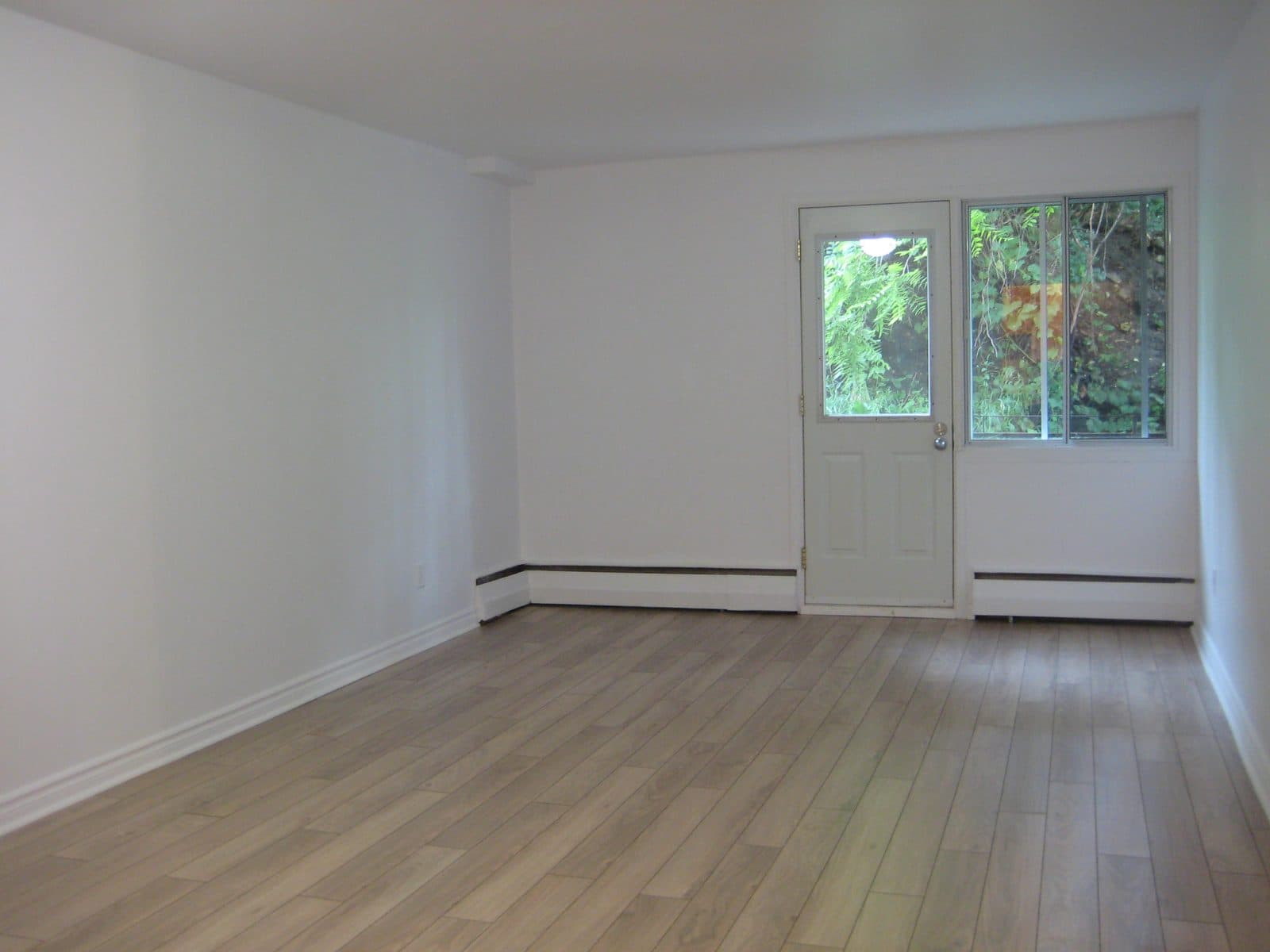 Bright living area with hardwood-look flooring and a private balcony door